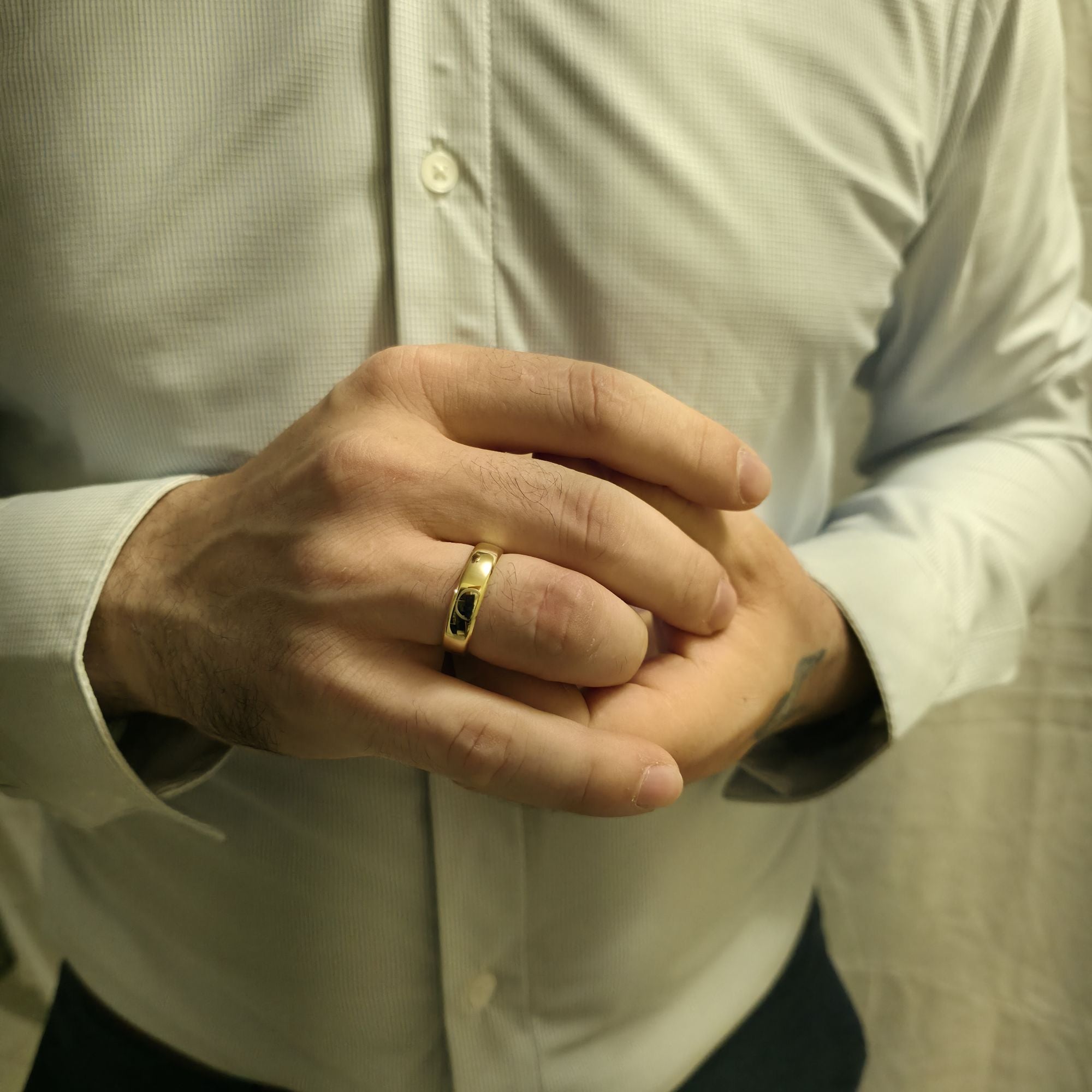 Man wearing a 6mm comfort fit wedding ring in 14K yellow gold, classic band with softly rounded edges and smooth polished finish.