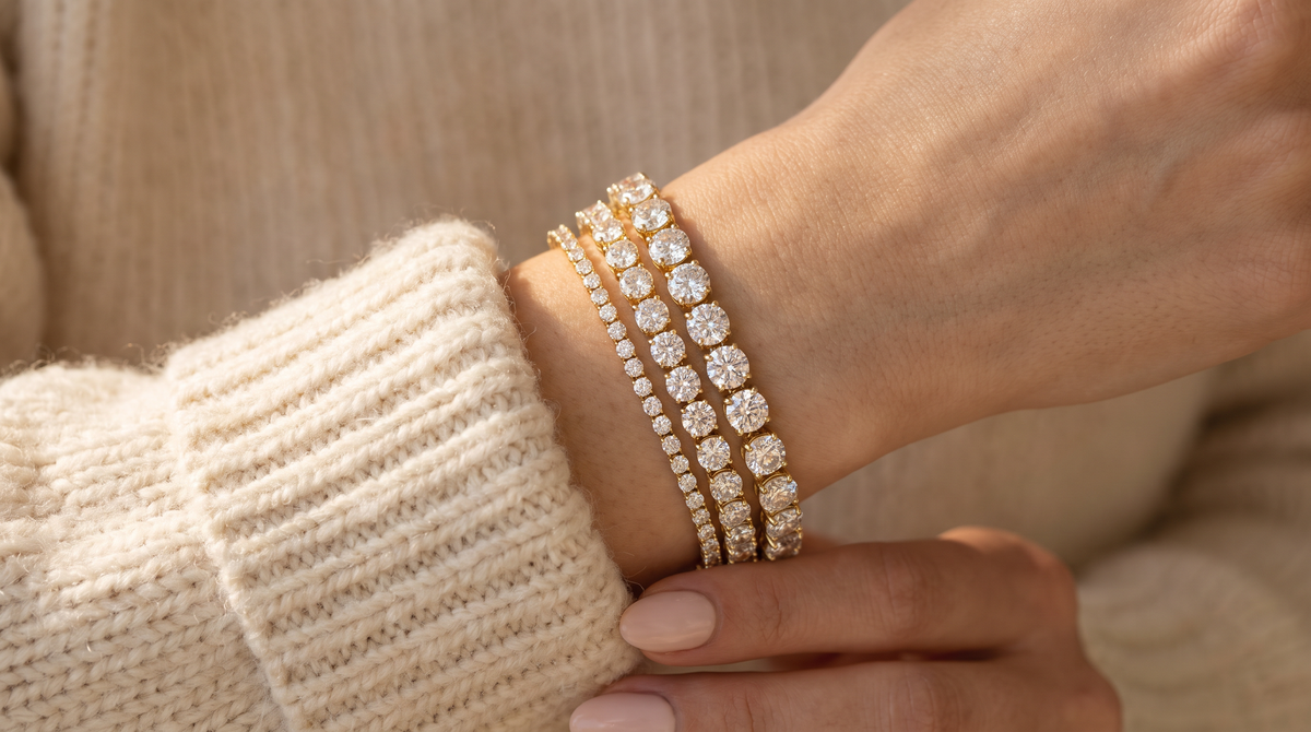 Three diamond tennis bracelets of increasing carat weight stacked on a wrist