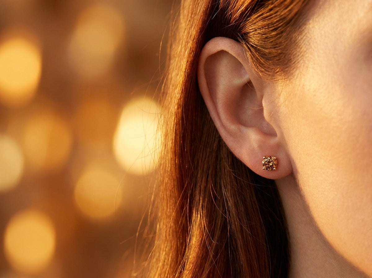 Close-up of ear wearing small round cognac diamond stud earrings in 14K yellow gold — Brownstone Earrings by Black Pearl of Queens