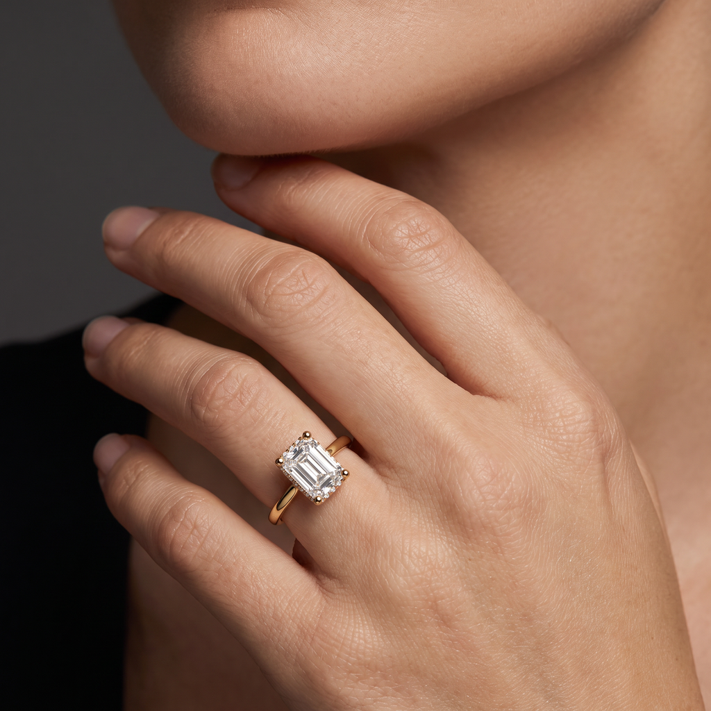 Hand wearing a 1.5 carat emerald cut Lab-Grown Diamond hidden halo engagement ring in 14K yellow gold