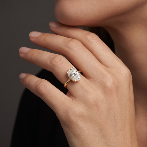 1.5 carat oval Lab-Grown Diamond hidden halo engagement ring on the hand, 14K yellow gold
