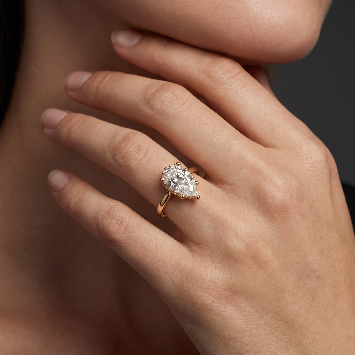 Hand wearing a 1.5 carat pear shaped Lab-Grown Diamond hidden halo engagement ring in 14K yellow gold