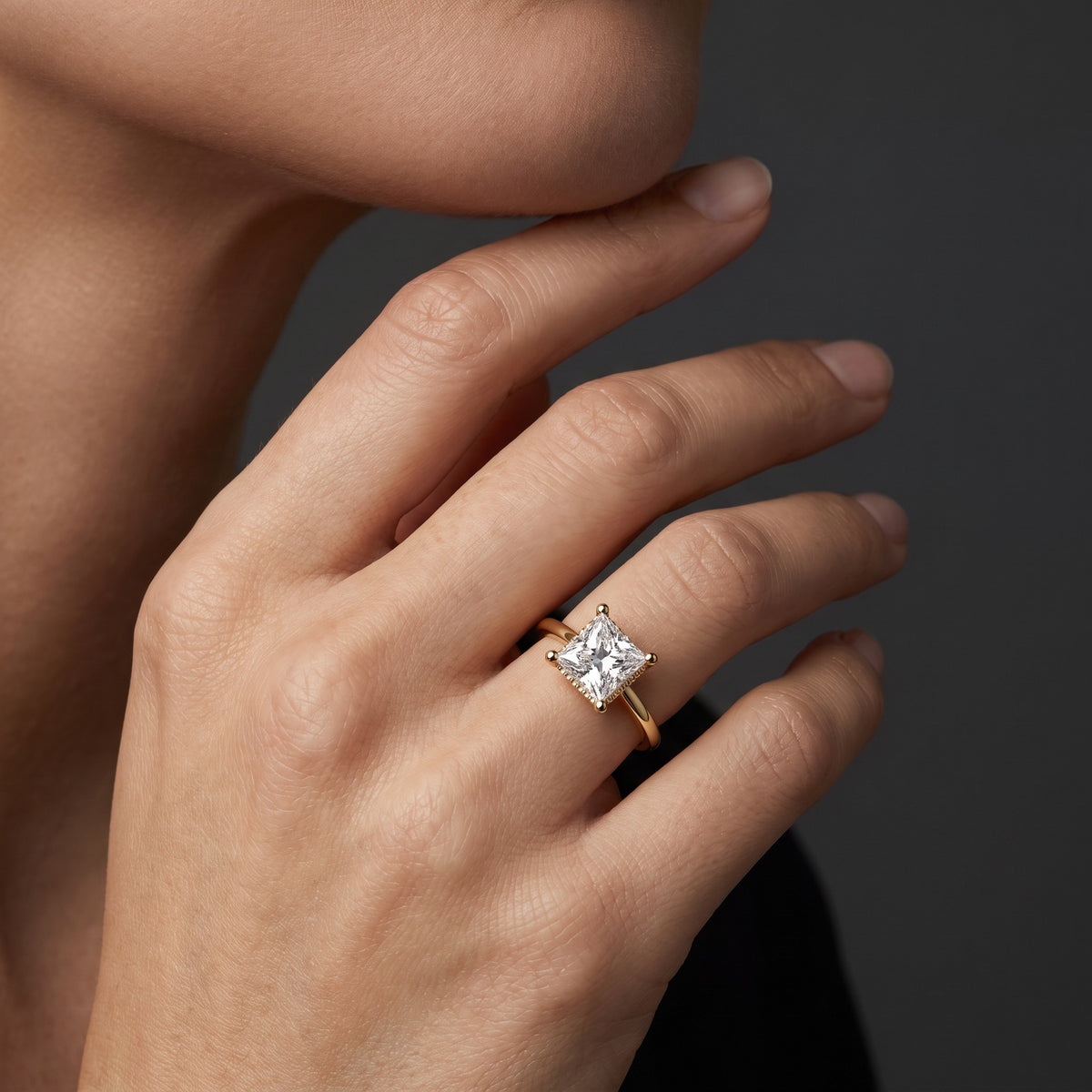 Hand wearing a 1.5 carat princess cut Lab-Grown Diamond hidden halo engagement ring in 14K yellow gold
