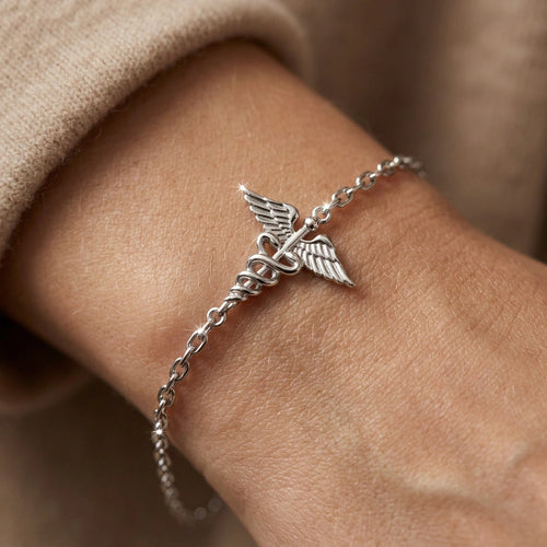 14K white gold caduceus charm bracelet worn on wrist close-up — delicate cable chain lifestyle view