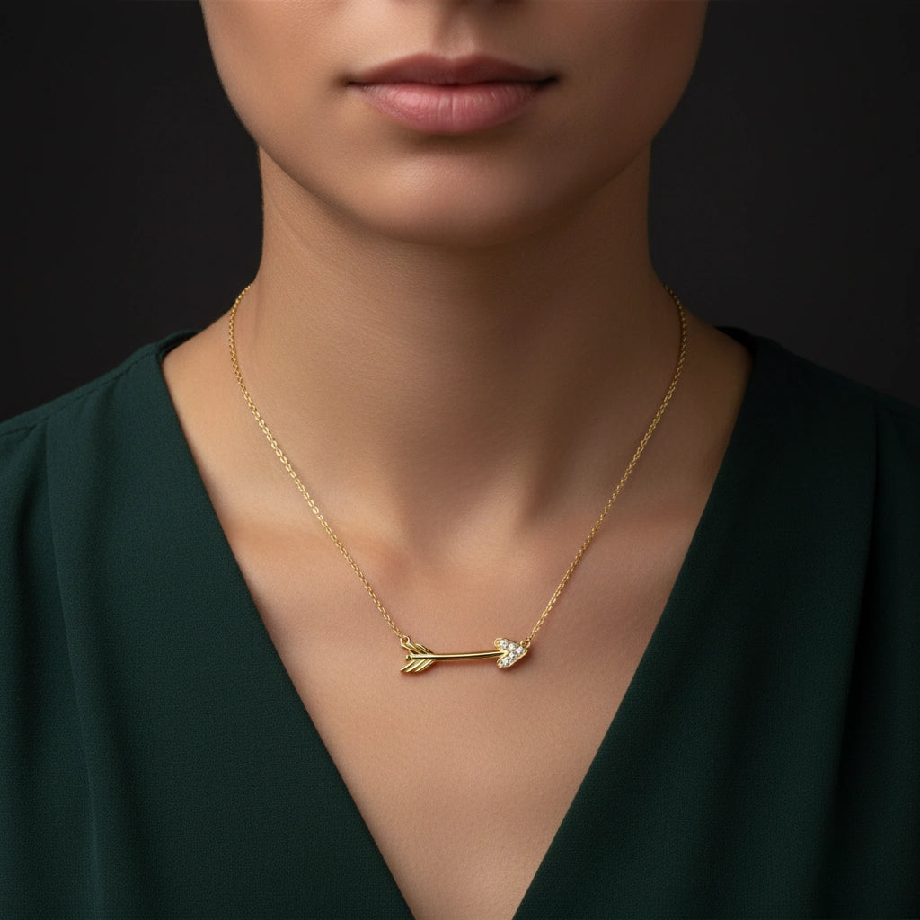 Close-up of 14K gold diamond arrow necklace on model wearing deep green silk top, Black Pearl of Queens fine jewelry