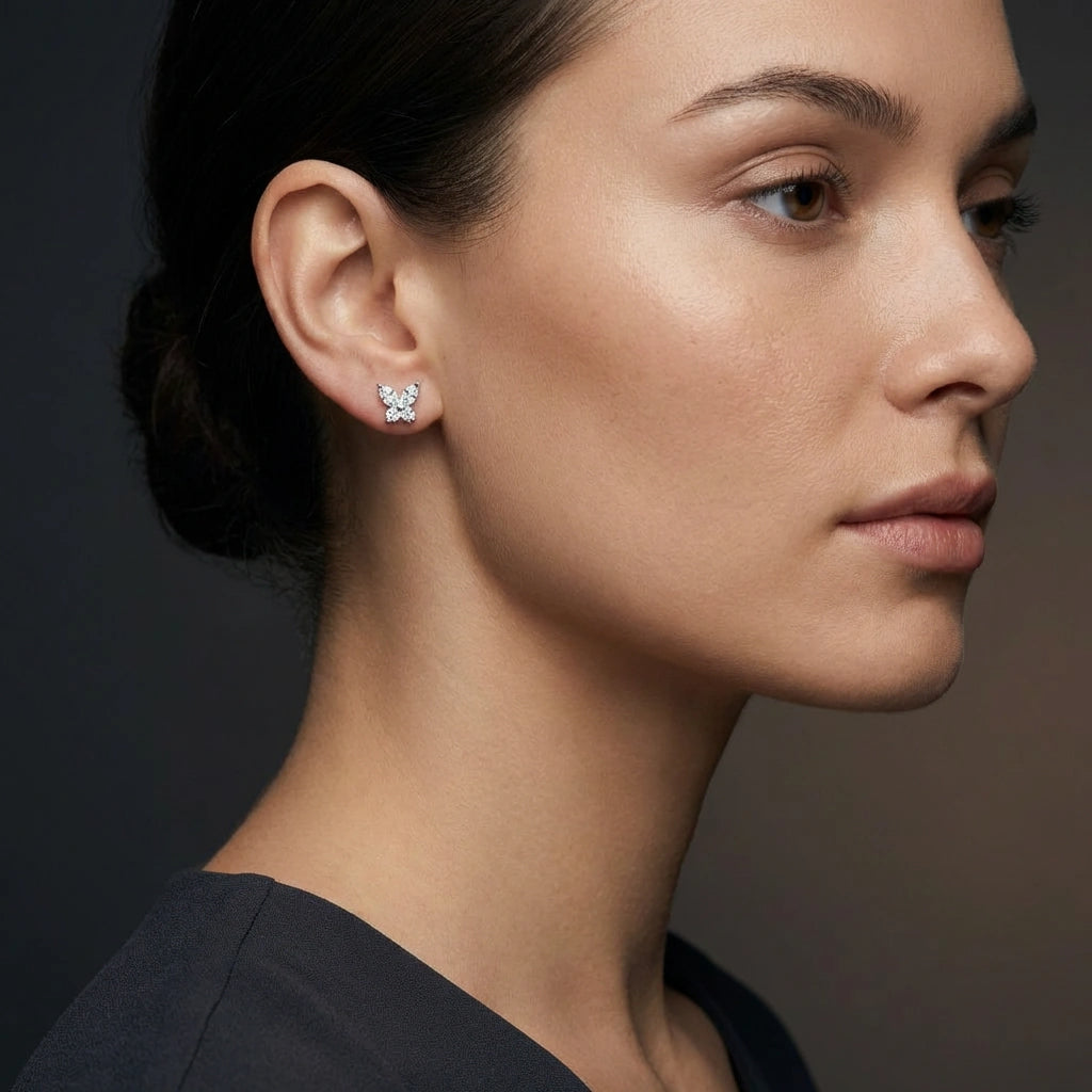 Close-up of 14K white gold diamond butterfly stud earrings worn on ear