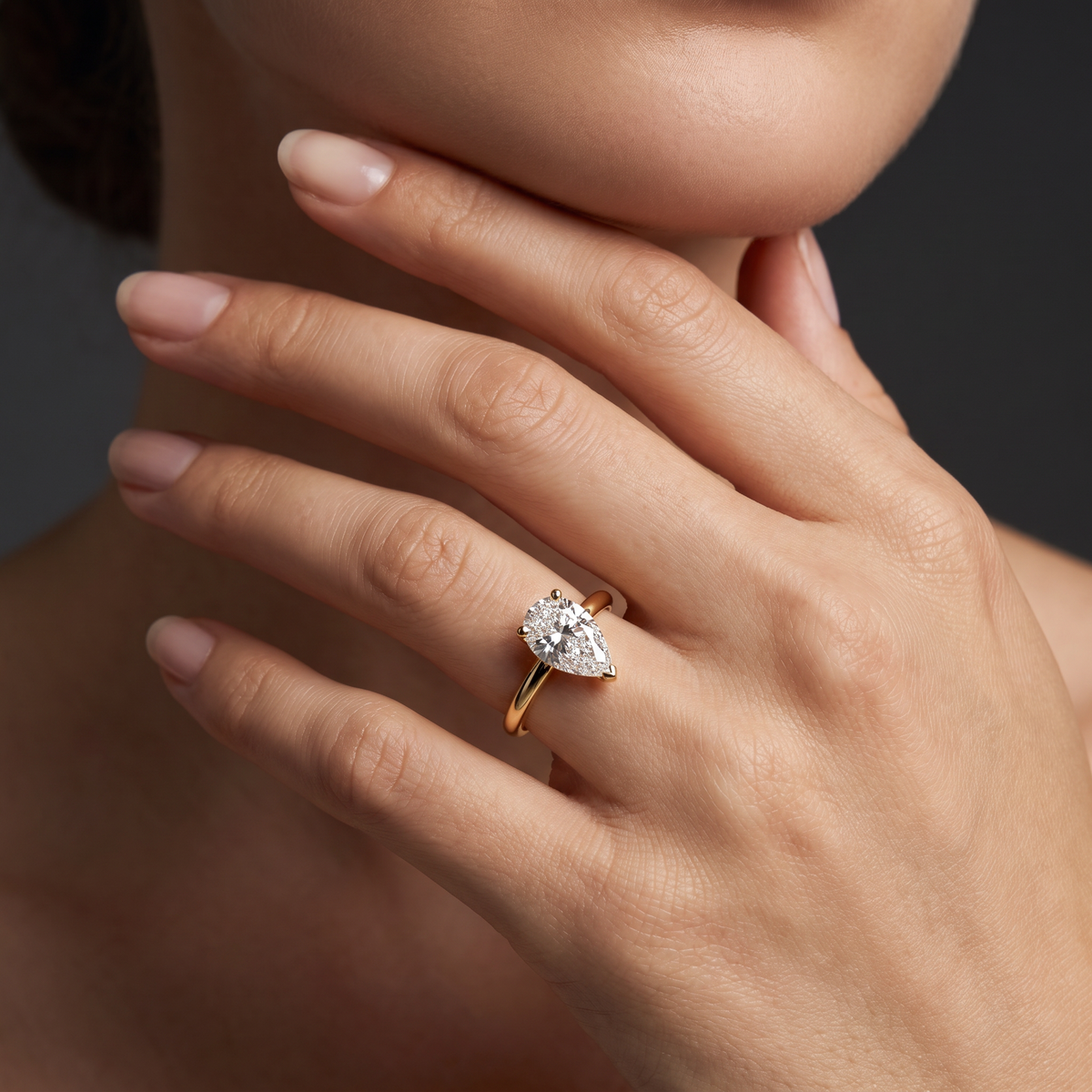 1ct pear solitaire engagement ring in 14K yellow gold worn on hand, point facing the fingertip