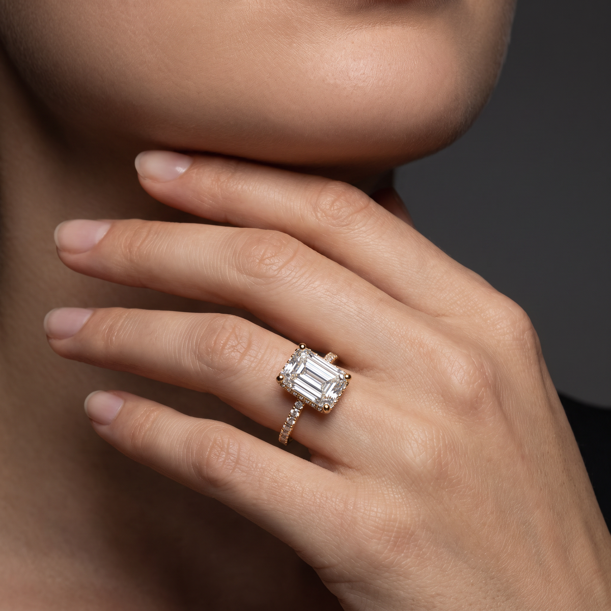 2.5ct emerald cut Lab-Grown Diamond engagement ring in 14K rose gold worn on hand, hidden halo pavé band setting