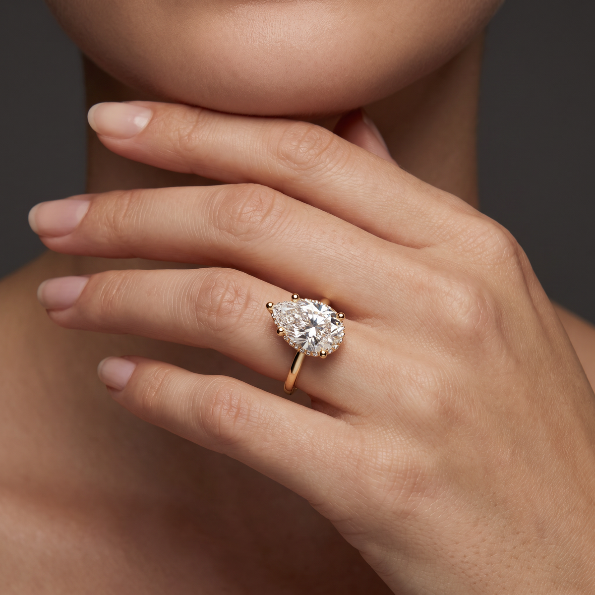Hand wearing a 2.5 carat pear shaped Lab-Grown Diamond hidden halo engagement ring in 14K yellow gold