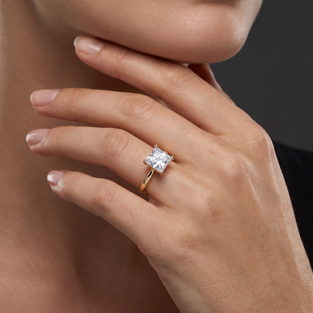 2.5ct princess cut diamond solitaire in 14K yellow gold worn on the hand, showing the stone's scale against the finger