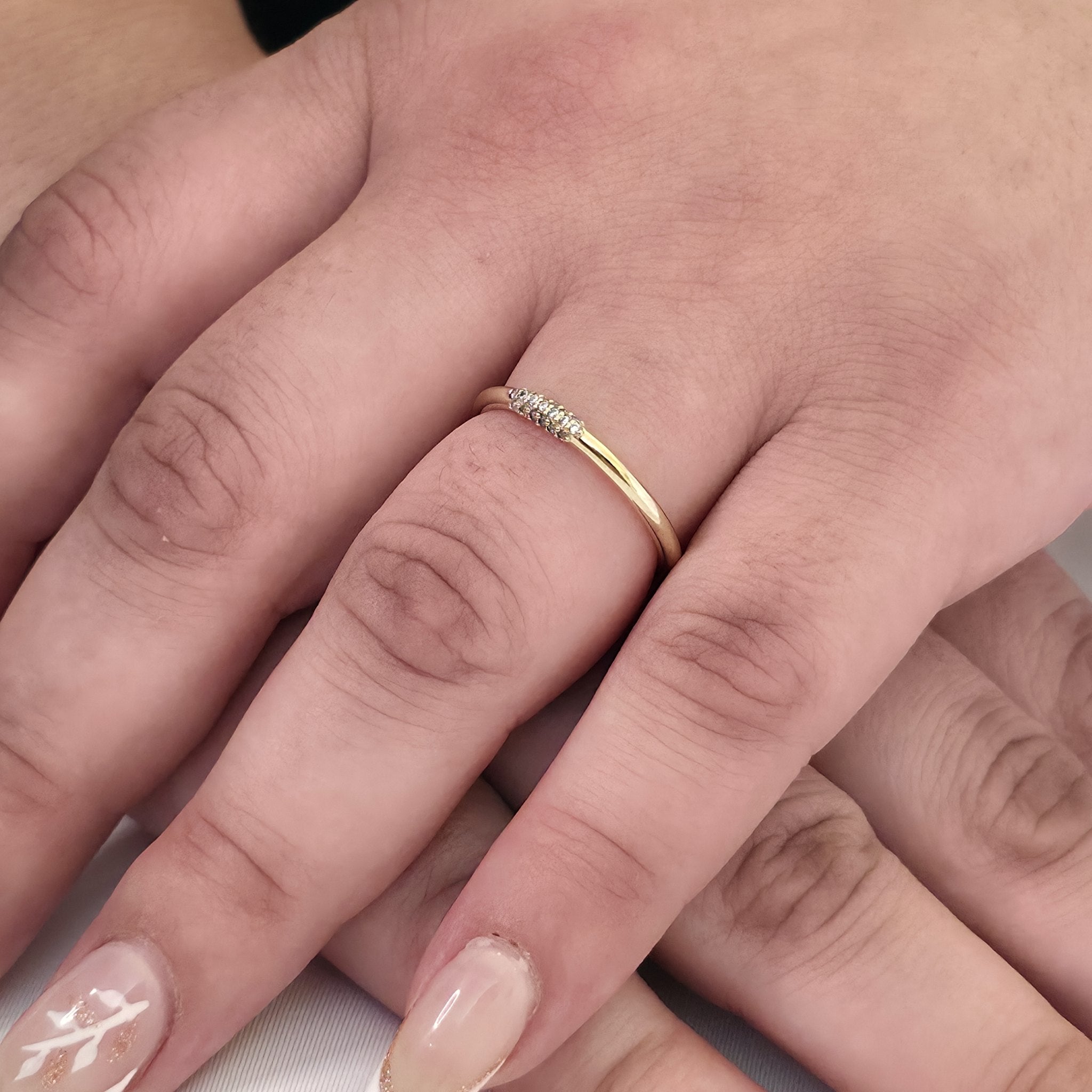 Stackable rings in 14K gold on hand – petite diamond wire ring paired with a pavé band for a modern wedding stack