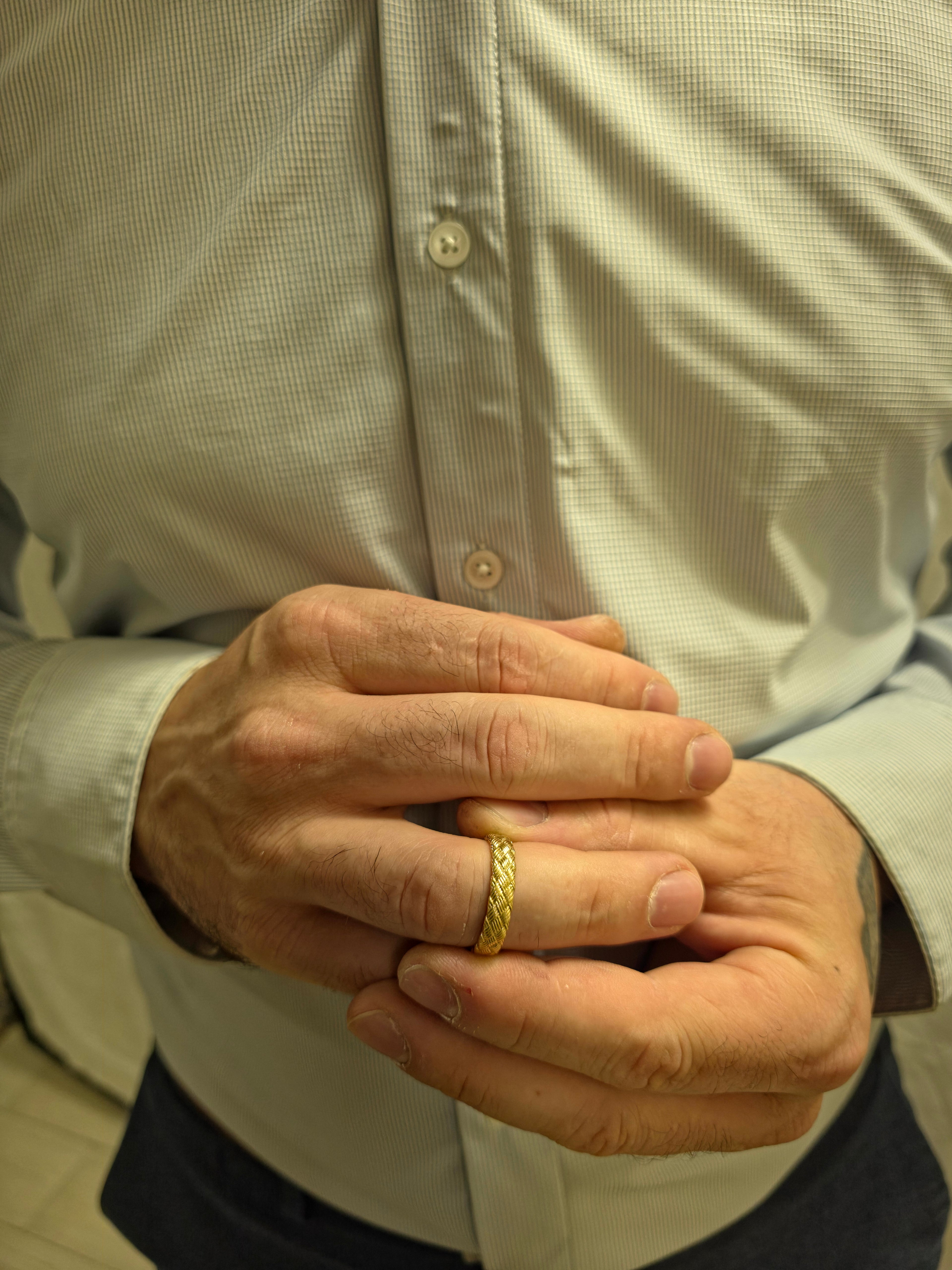 Close-up of a person wearing a gold ring with a neutral background