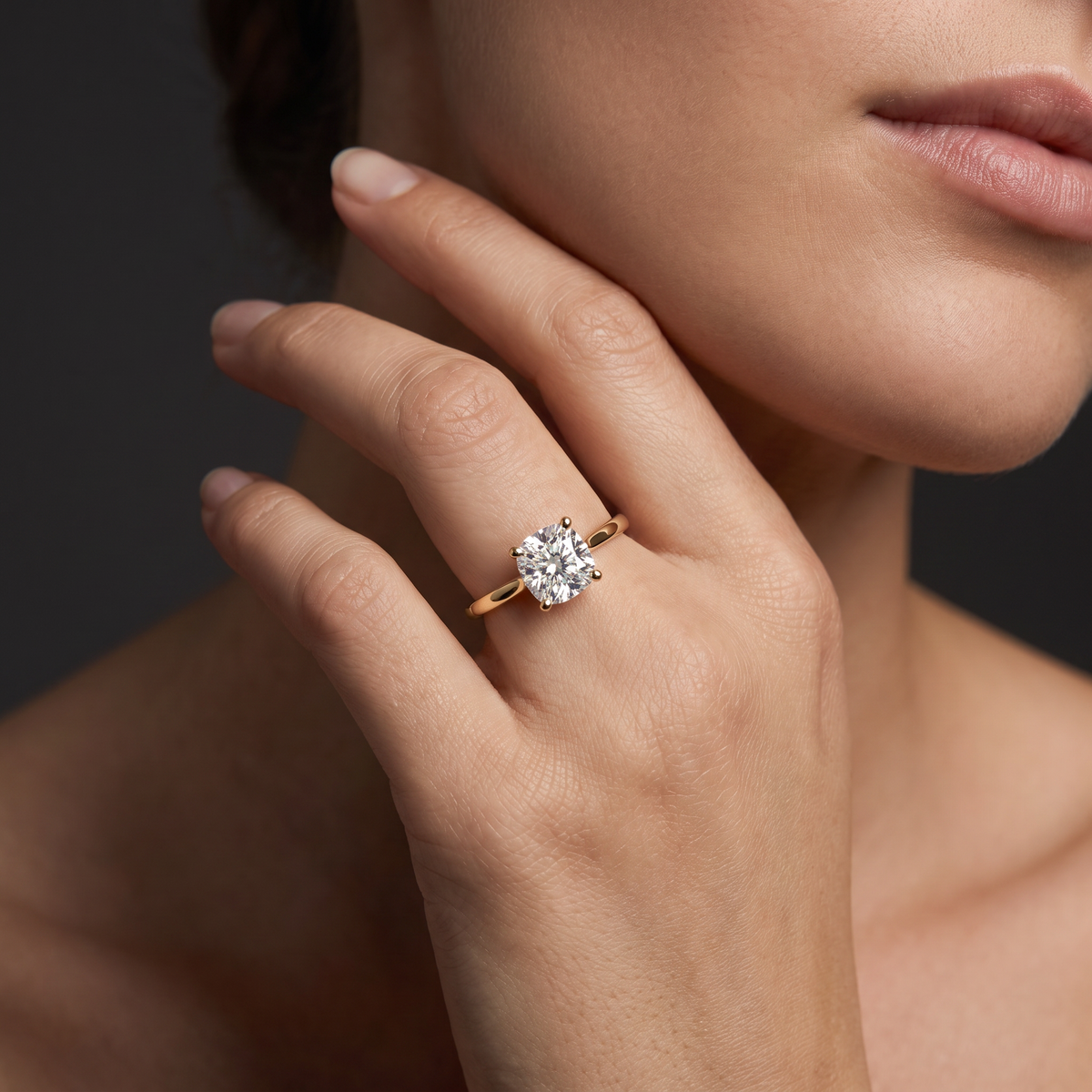 2ct cushion cut diamond solitaire in 14K yellow gold worn on the hand, showing the stone's scale against the finger