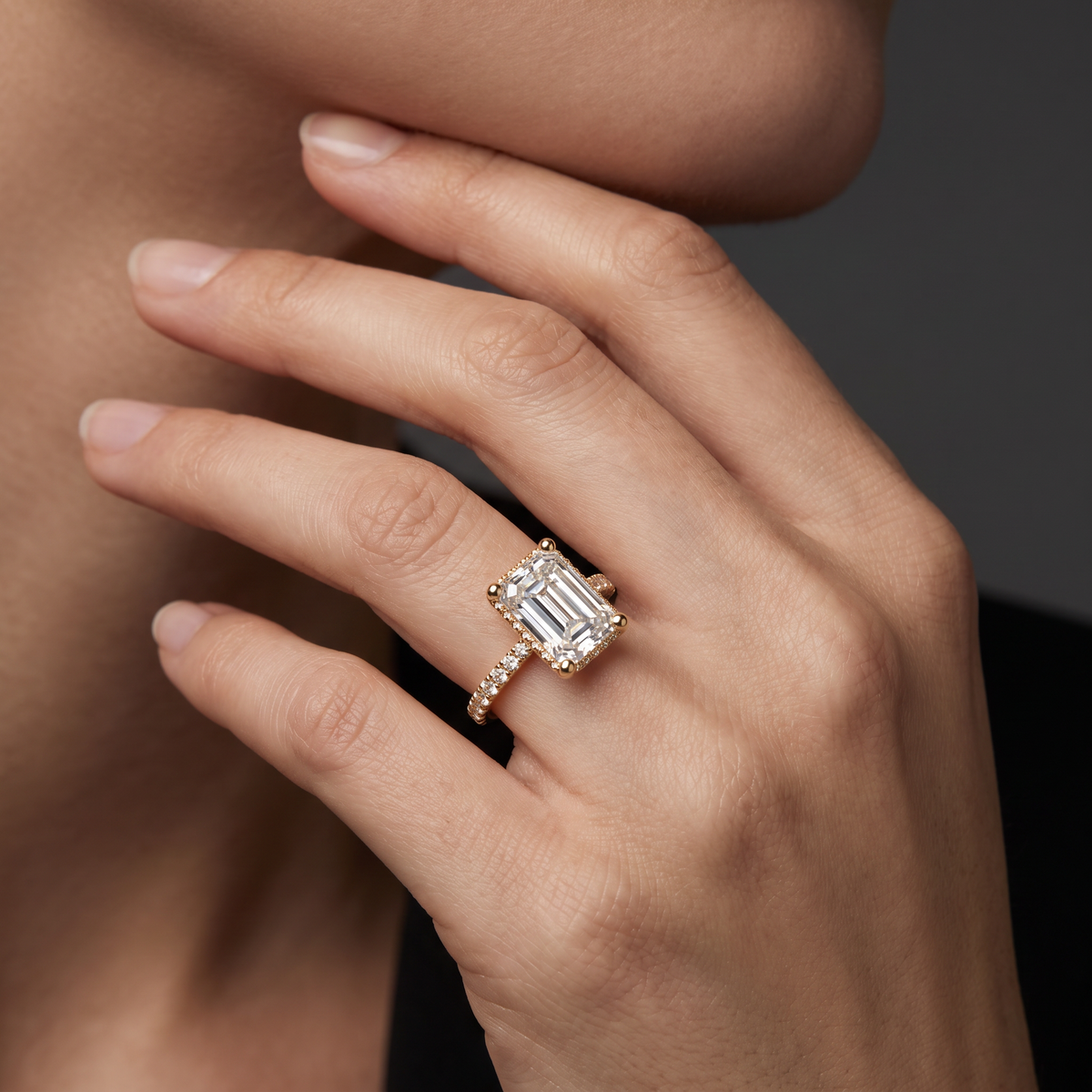 2ct emerald cut Lab-Grown Diamond engagement ring in 14K rose gold worn on hand, hidden halo pavé band setting