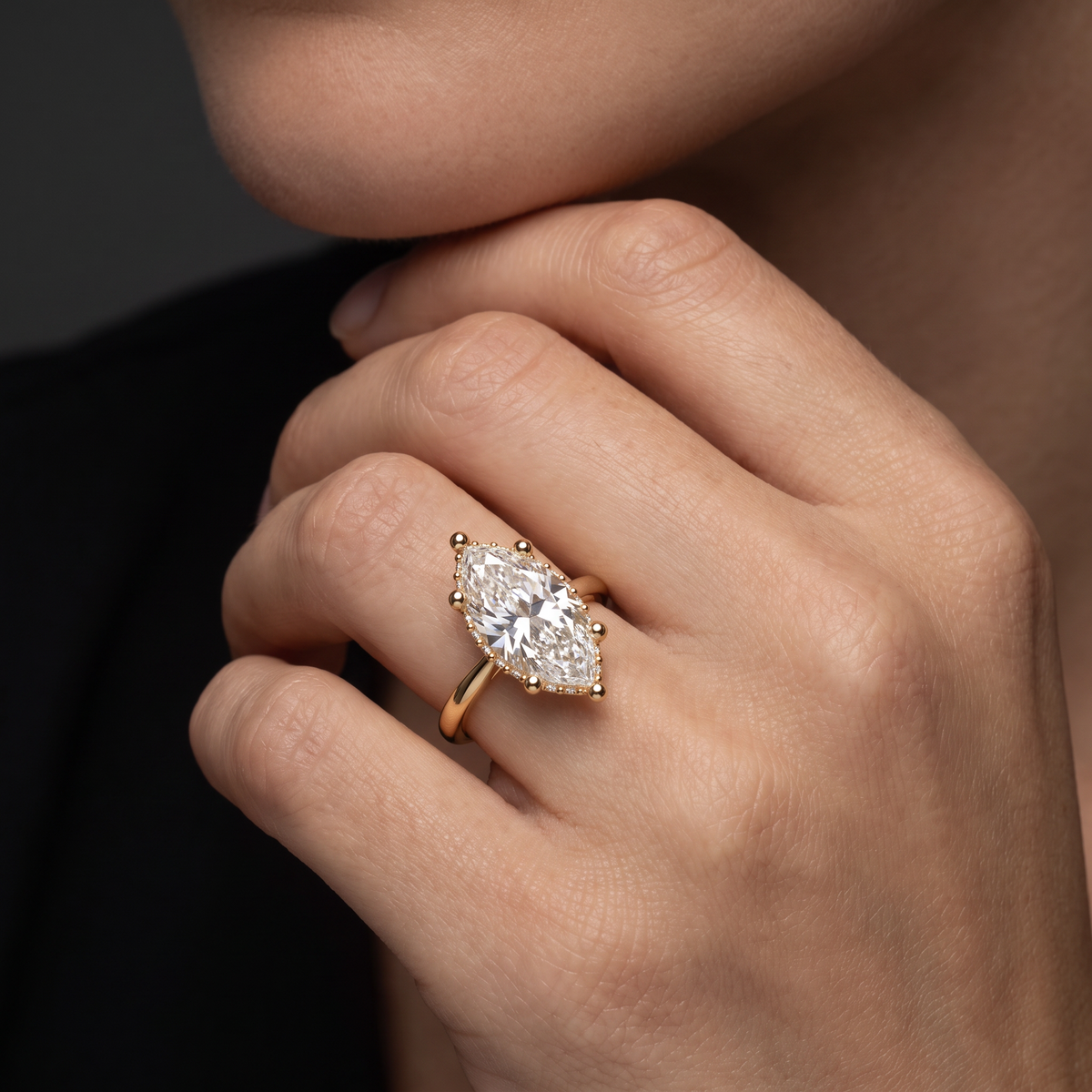 Hand wearing a 2 carat marquise Lab-Grown Diamond hidden halo engagement ring in 14K yellow gold