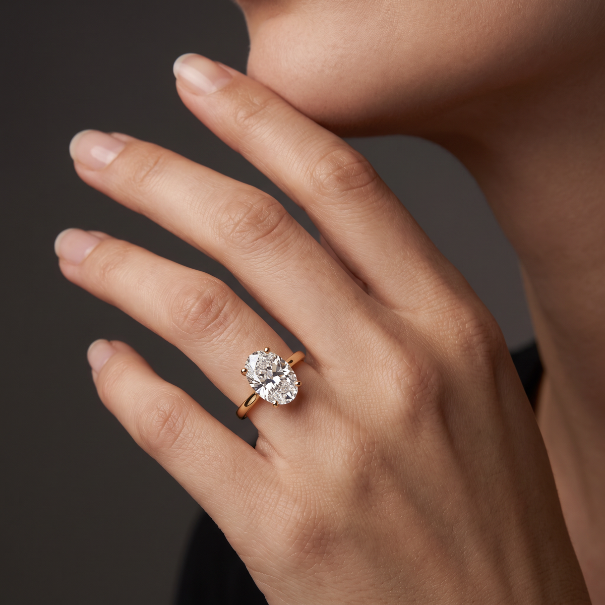 2ct oval cut diamond solitaire in 14K yellow gold worn on the hand, showing the stone's length along the finger