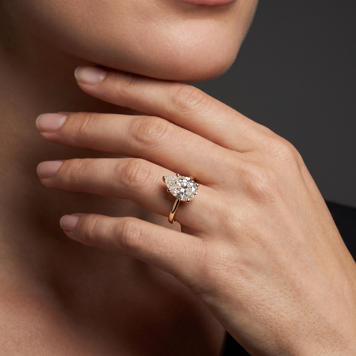 2ct pear cut diamond solitaire in 14K yellow gold worn on the hand, point facing the fingertip