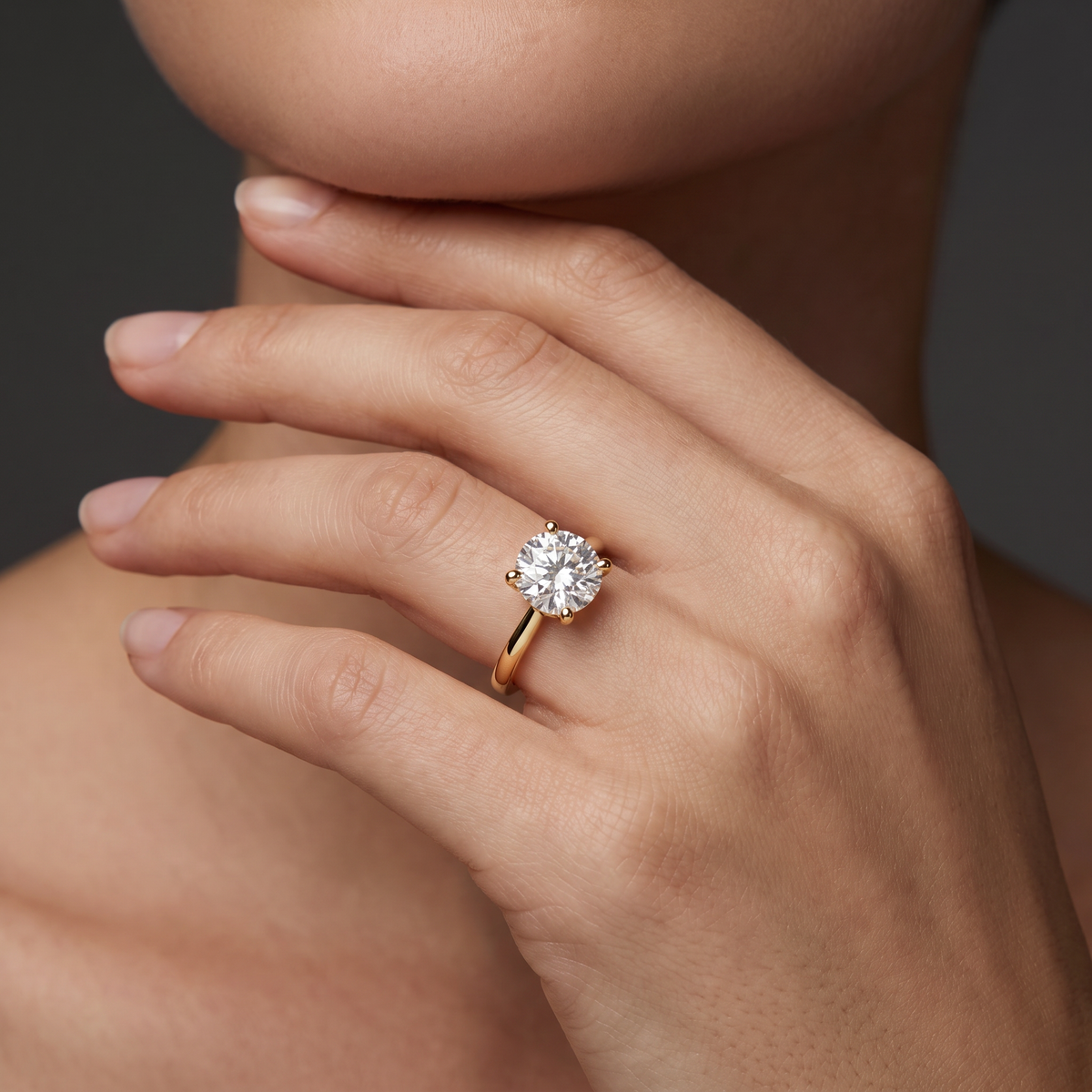 2ct round diamond solitaire in 14K yellow gold worn on the hand, showing the stone's scale against the finger