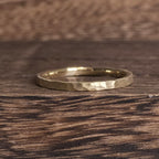 Close-up of a 2mm hammered texture gold wedding band with satin finish, minimalist handmade design by Black Pearl of Queens.