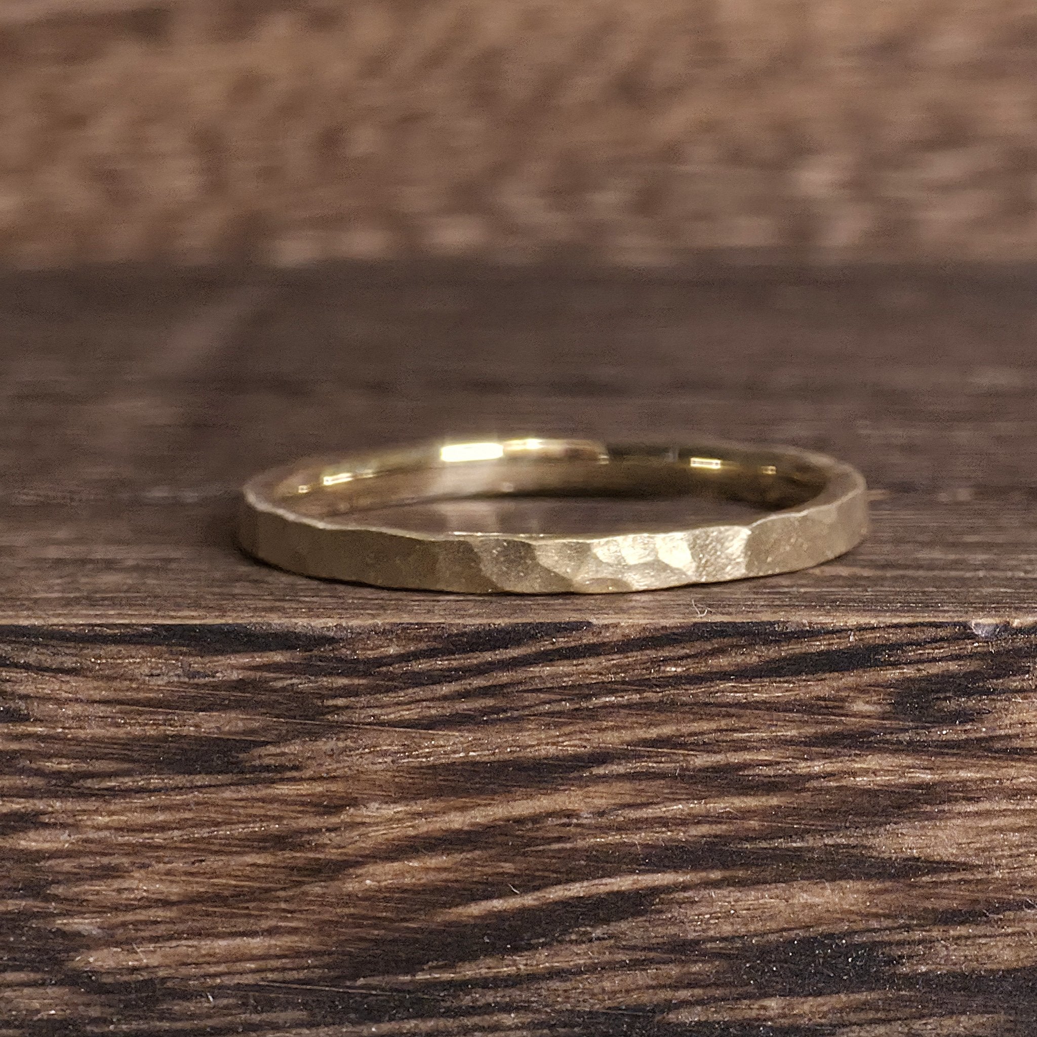 Close-up of a 2mm hammered texture gold wedding band with satin finish, minimalist handmade design by Black Pearl of Queens.