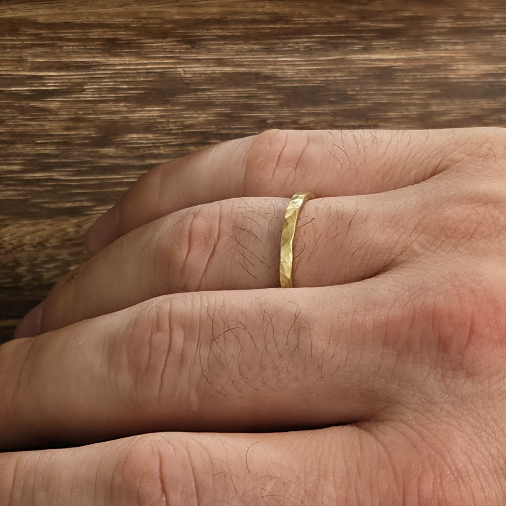 2mm hammered gold wedding band with matte satin finish shown on hand, handcrafted minimalist ring from Black Pearl of Queens.
