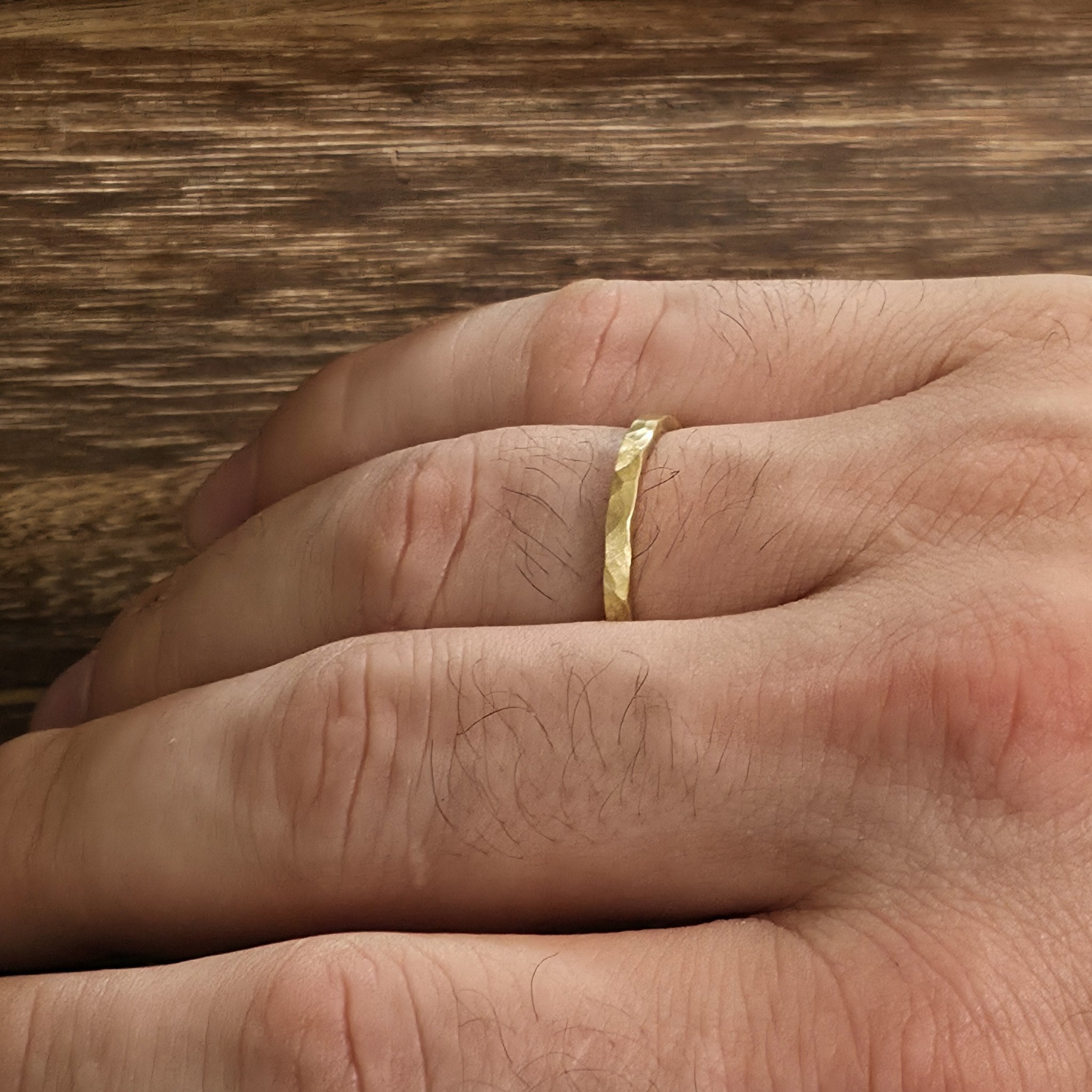 2mm hammered gold wedding band with matte satin finish shown on hand, handcrafted minimalist ring from Black Pearl of Queens.