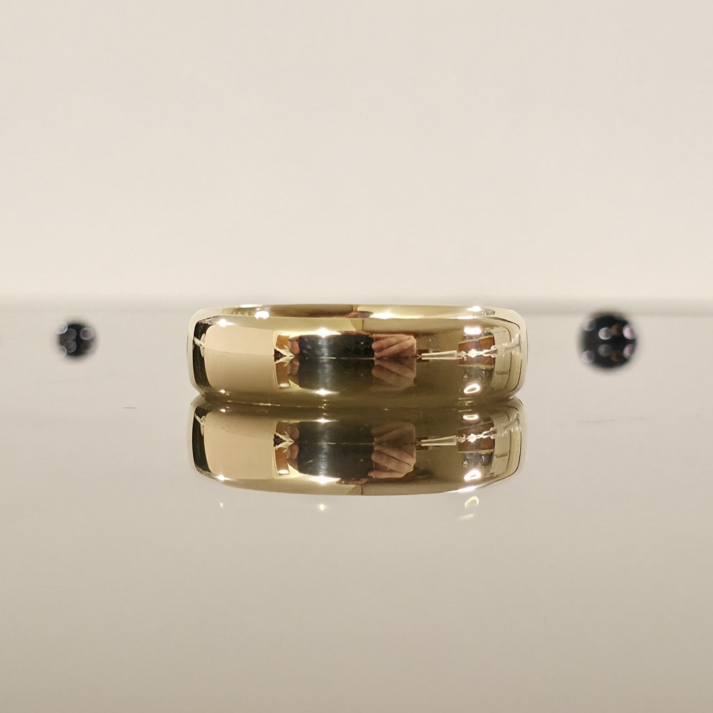 rounded edge 6mm comfort fit wedding ring in gold laid down and closed up view - Black Pearl of Queens