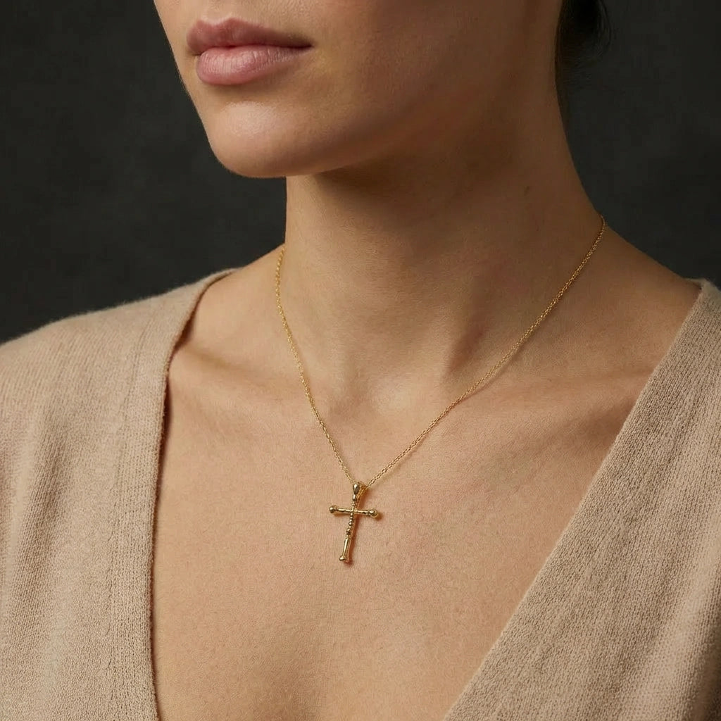 Woman wearing 14K gold Faithline cross necklace with delicate beveled pendant on collarbone
