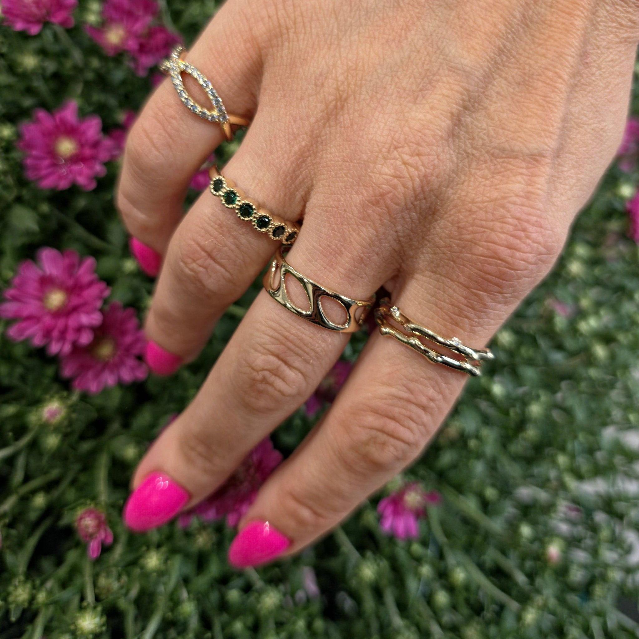 Olive leaf gold band stacked with other rings on hand with pink nails