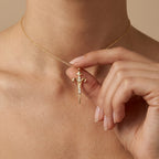 Model holding Aurex Aries Zodiac Diamond Necklace in 14K yellow gold at décolletage, warm editorial close-up showing pendant detail