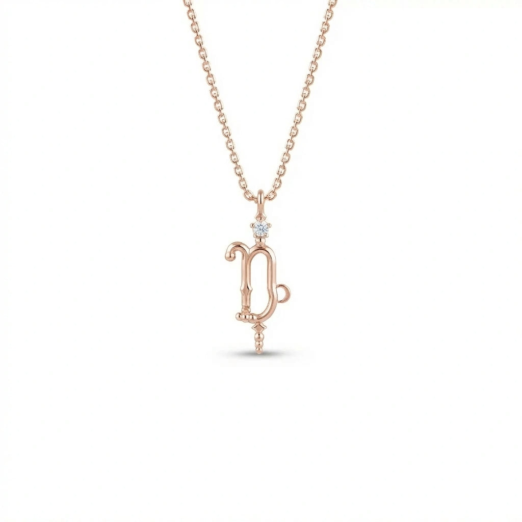Aurex Capricorn Zodiac Diamond Necklace in 14K rose gold, front view showing sculptural Capricorn glyph with diamond crown and beaded drop on cable chain