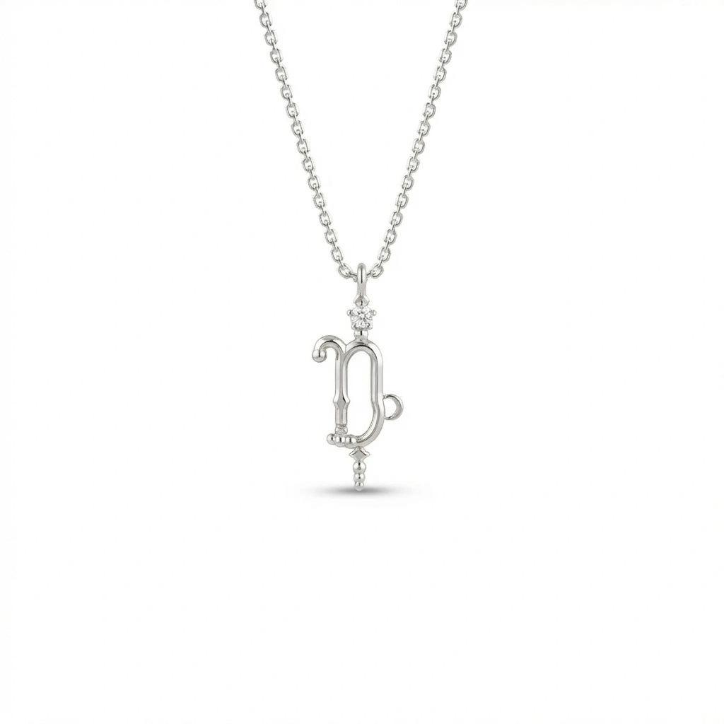 Aurex Capricorn Zodiac Diamond Necklace in 14K white gold, front view showing sculptural Capricorn glyph with diamond crown and beaded drop on cable chain
