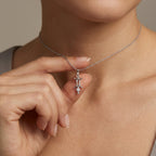 Model holding Aurex Gemini Zodiac Diamond Necklace in 14K white gold between fingers at décolletage, close-up editorial shot showing twin pillar symbol and diamond drop detail