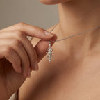 Model holding Aurex Pisces Zodiac Diamond Necklace in 14K white gold between fingers at décolletage, close-up editorial shot showing sculptural cross form with crescent moon top and center diamond