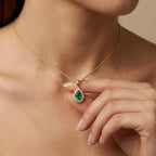 Woman wearing Aveline emerald halo pendant in yellow gold with pear shaped green emerald and diamond halo design