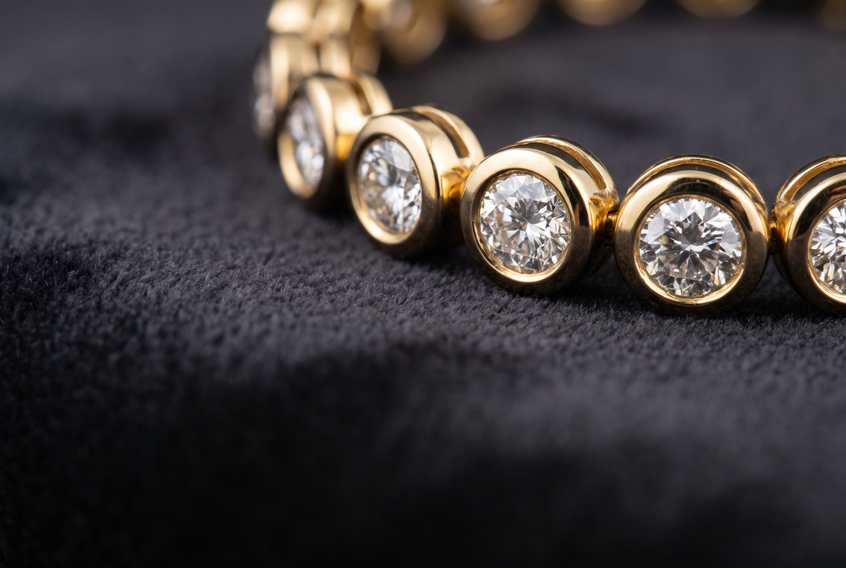Close-up of bezel-set diamonds in a 14K yellow gold tennis bracelet, each stone protected by a gold rim