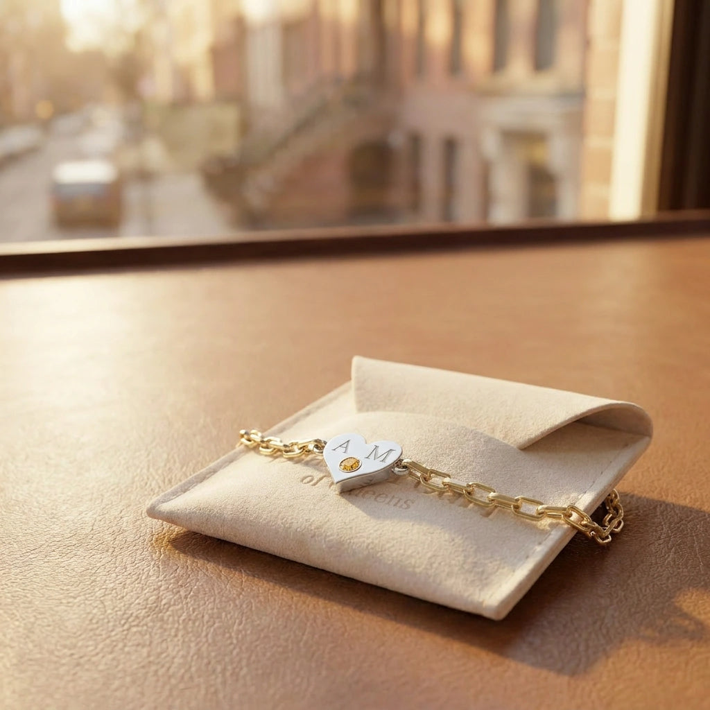 Brownstone champagne diamond heart bracelet resting on Black Pearl of Queens cream suede pouch with NYC brownstone buildings in golden hour window light