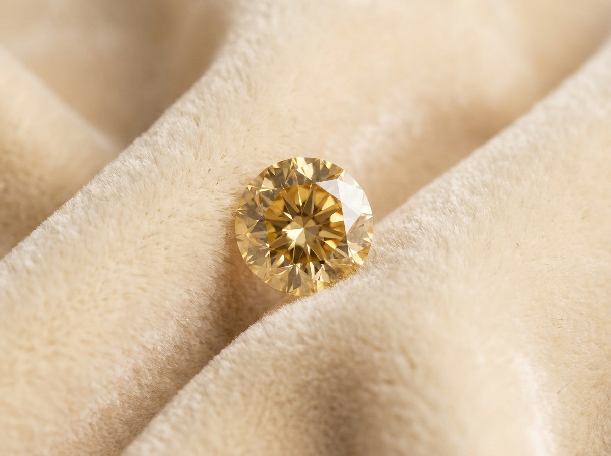 Loose champagne diamond C3, golden honey tone with brilliant facets, resting in soft cream velvet folds — natural fancy color diamond, Champagne Diamond Guide by Black Pearl of Queens