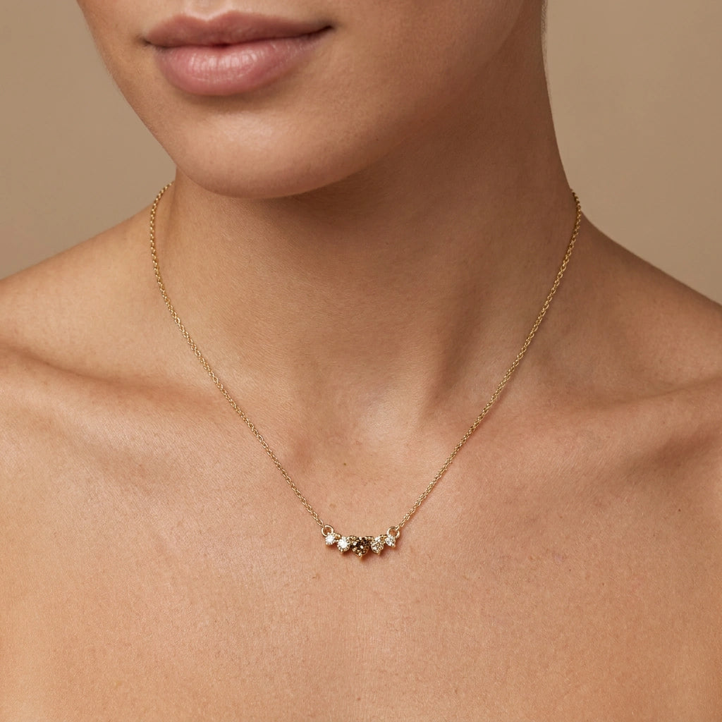 Model wearing graduated five-stone cognac and champagne diamond curved bar necklace in 14K yellow gold at collarbone — Black Pearl of Queens