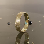 6mm brushed gold wedding band standing upright showing matte texture and comfort fit interior