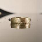 Close-up of brushed gold wedding band with matte finish, 14K 6mm handcrafted ring reflection photo