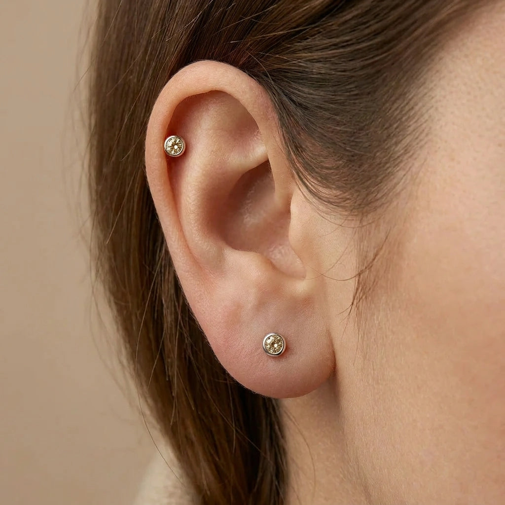 Natural champagne diamond bezel stud earring in 14K white gold worn on ear — close-up lifestyle view