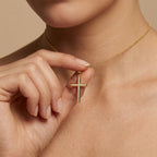 Woman holding channel-set diamond cross pendant in 14K gold - sleek contemporary cross necklace