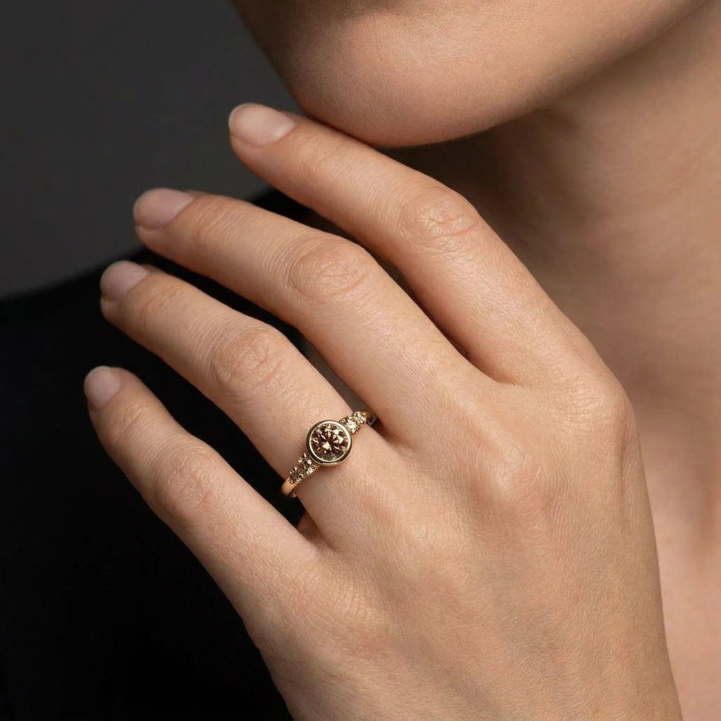 Natural cognac diamond bezel engagement ring worn on hand, deep amber stone close-up