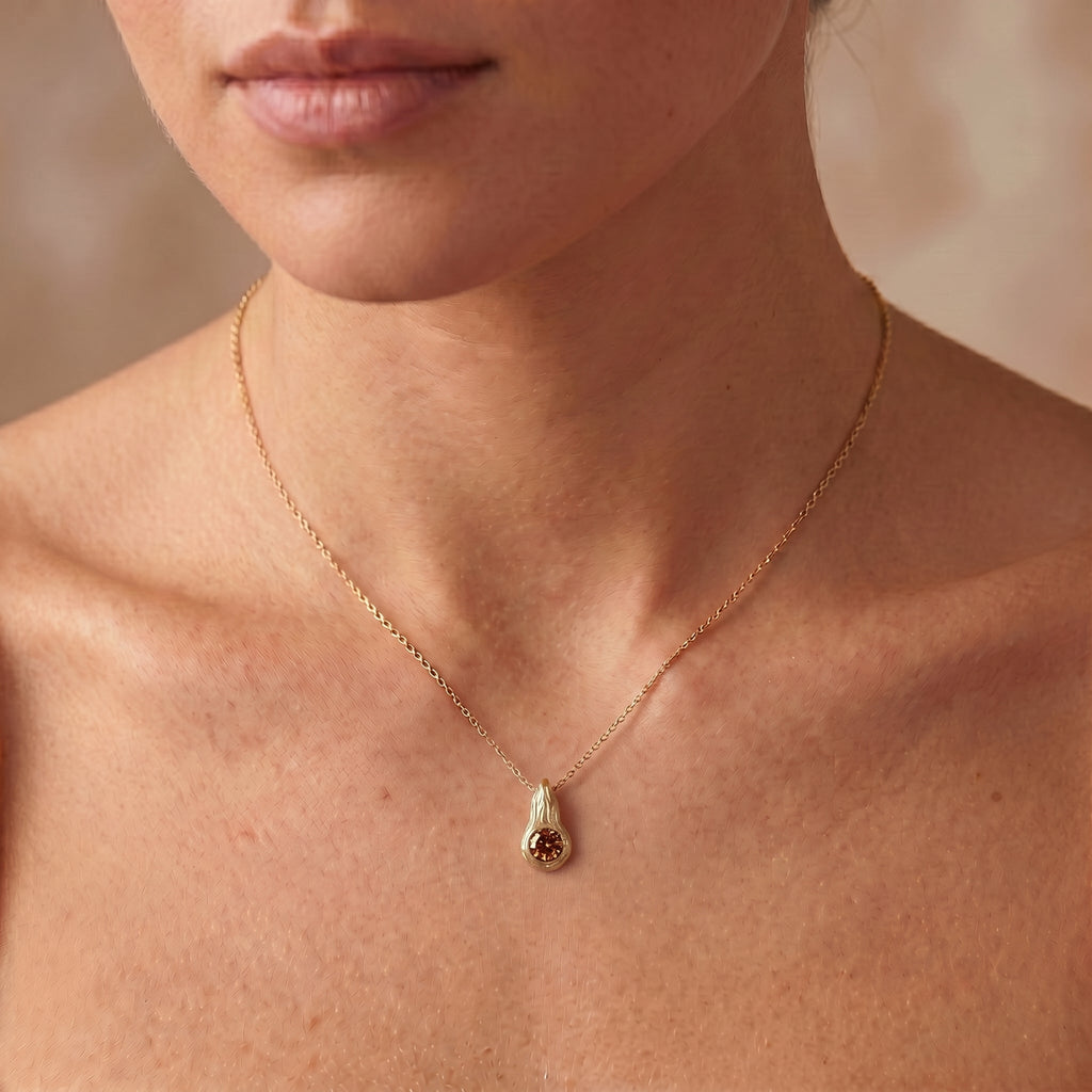 Cognac diamond Ember pendant worn on the neck, 14K yellow gold flame design