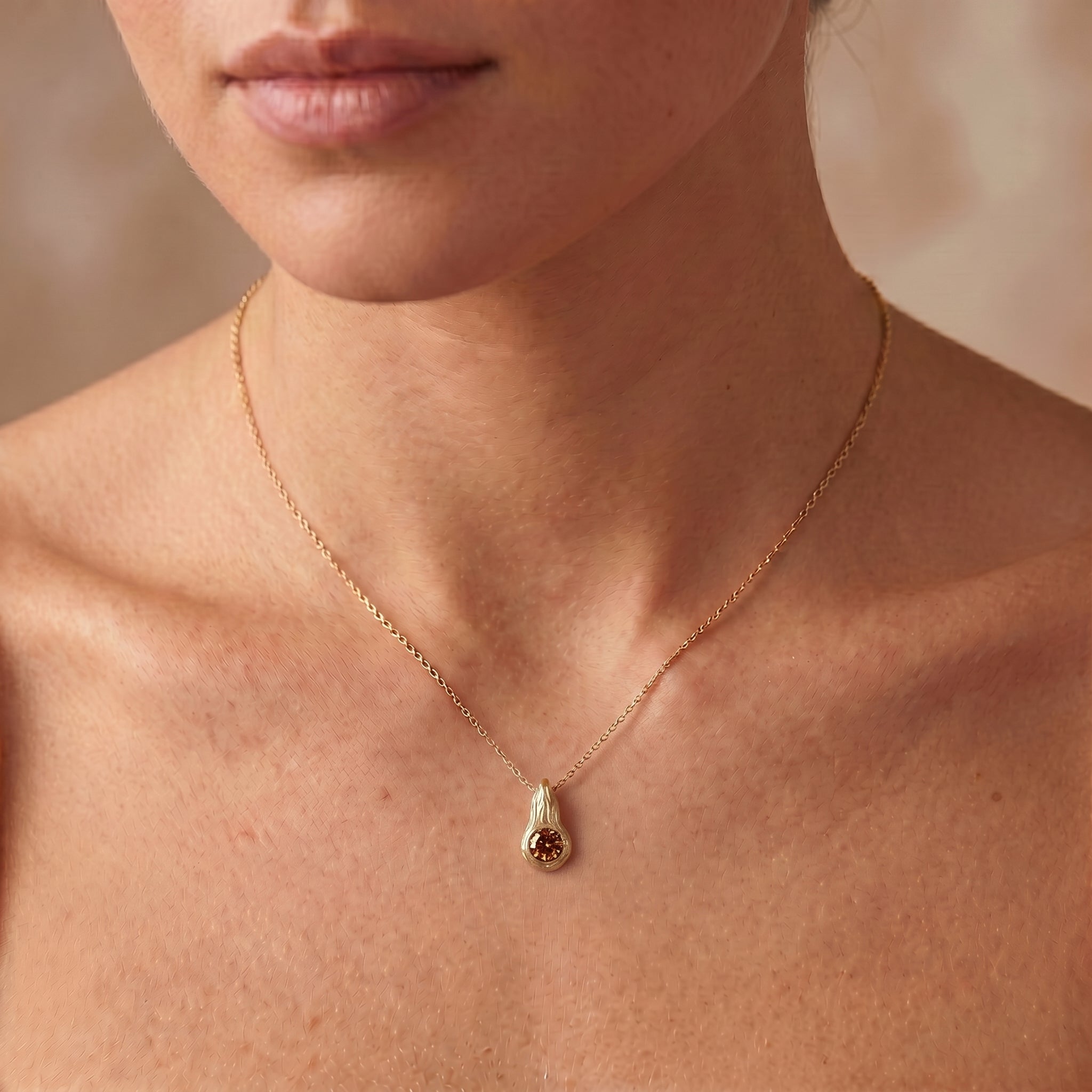 Cognac diamond Ember pendant worn on the neck, 14K yellow gold flame design