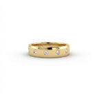 Cyrus Diamond Station Band in 14K yellow gold, front view on white background showing wide domed band with 12 flush bezel-set D-F colorless lab diamonds in scattered station arrangement