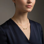 Woman wearing a 14K solid yellow gold diamond arrow necklace styled with deep navy silk blouse in luxury studio setting