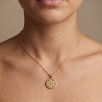 Woman wearing diamond honeycomb medallion pendant necklace in solid 14K yellow gold on the collarbone — Black Pearl of Queens