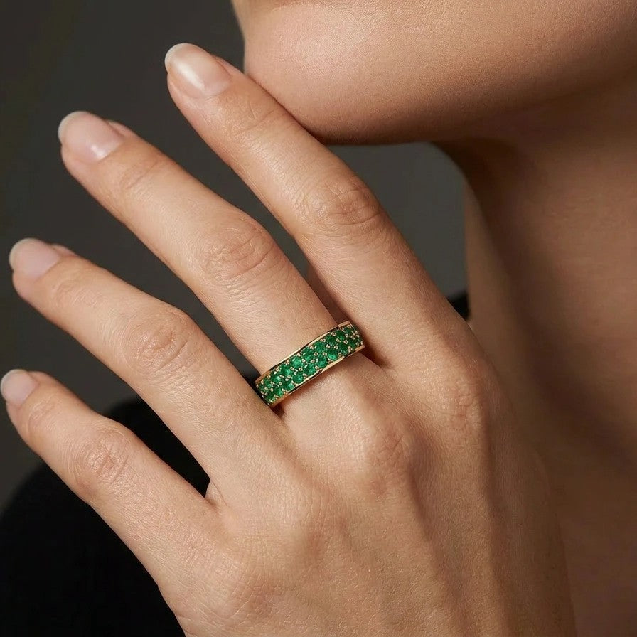 Double row emerald eternity ring worn on hand in 14K gold with pavé green gemstones
